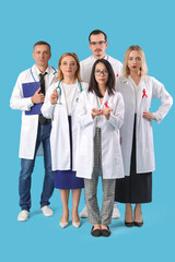 Professional team of doctors with red ribbons on blue background. World AIDS Day concept