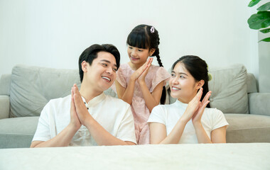 Asian family playing a clapping game like pat-a-cake, smiling and looking at each other.