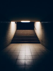 Illuminated Staircase in a Dark Underground Passageway. A dimly lit stairway leading upwards, offering a dramatic perspective.