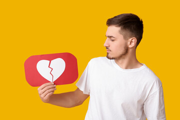 Handsome young man with heart dislike icon on yellow background