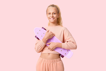 Happy teenager girl with skateboard on pink background