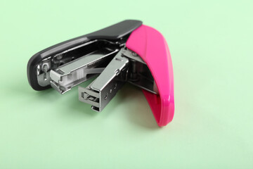 Pink stapler on green background