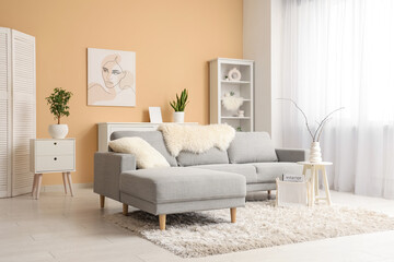 Interior of stylish living room with grey sofa, coffee table, shelving unit and picture