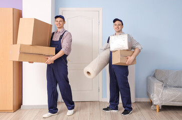 Loaders carrying carpet and cardboard boxes in room