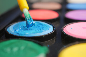Colorful art supplies displayed with a brush applying paint