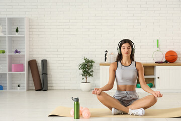 Young woman listening to music and meditating in gym