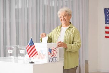 Voting senior woman near ballot box with USA flag at polling station