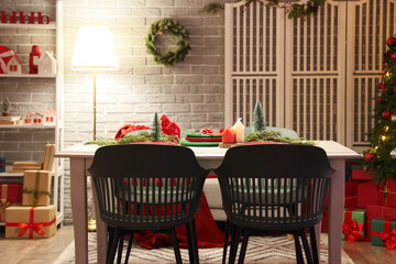 Interior of dining room decorated for Christmas with table and glowing lamp
