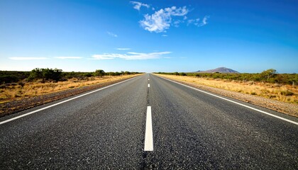 Naklejka premium Straight Asphalt Road Leading To Horizon Under Blue Sky With Mountain In Background