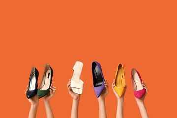 Female hands with stylish shoes against color background