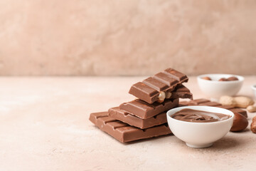 Bowl of sweet chocolate spread and hazelnuts on beige background