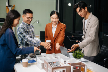 Asian architects and designers brainstorming and collaborating in a modern office, utilizing models and plans