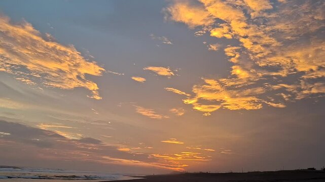 Tropical Black Sand Beach with Stunning Golden Sky, Calm Ocean Waves Gently Sweeping, Orange Light Illuminating the Sky and Ocean, Calming and Peaceful Sunset Atmosphere, Exotic and Natural Landscape 