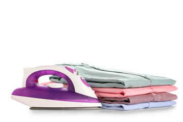 Modern electric iron with stack of folded clean shirts on white background