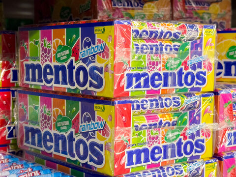 Stacked rainbow mentos display with vibrant packaging at supermarket