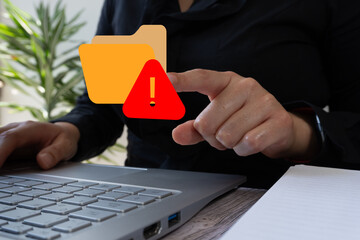Businesswoman working on computer, pointing at a folder icon with a warning sign