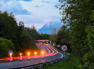 Light trails from cars passing roadworks on a mountain road at dusk