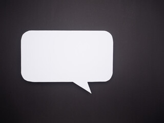 Fototapeta premium Blank white paper speech bubble cutout on black background.