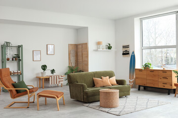 Interior of living room with surfboard, green sofa and armchair