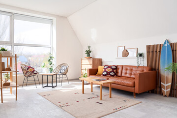 Interior of living room with surfboard, folding screen and brown sofa