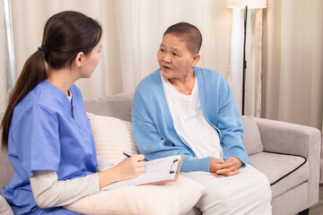 Young nurse in uniform listening attentively to an senior woman on a couch, expressing support and empathy in a friendly conversation about health and wellbeing, healthcare, medical, take care.