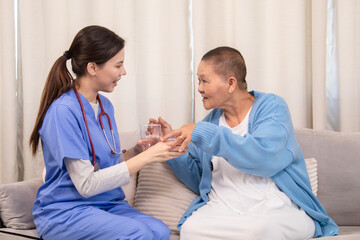 Nurse handing pill cup to senior woman, both engaging in daily care routine in cozy living room,...