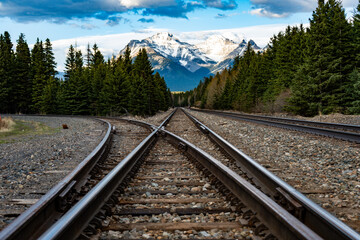 Converging train tracks with mountains and clear blue sky in the background