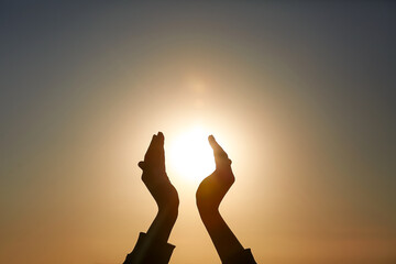 Fototapeta premium Silhouette of female hands holding sun at sunset. Summer solstice