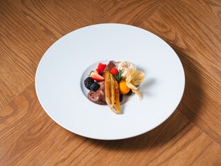 Chocolate mousse with caramelized banana, berries and vanilla ice cream on white plate