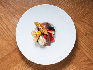 Chocolate mousse with caramelized banana, berries and vanilla ice cream on white plate
