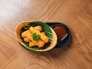 Deep fried cheese sticks in basket with dipping sauce on wooden table