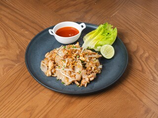 Thai stir-fried flat noodles with chicken and vegetables served on black plate