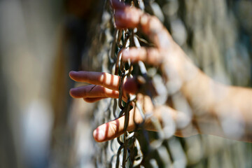 Hand Reaching Through Chain Link Fence in Natural Background