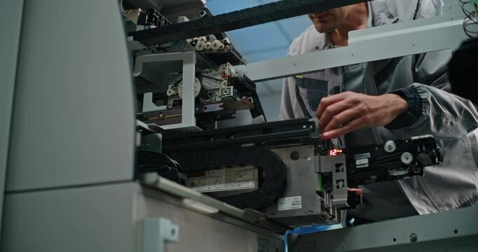 ATM Technician in Uniform Performing Maintenance of Cash Dispenser Machine. Male Worker Servicing ATM Machine in Modern Airport Terminal. Banking Technology, Cash Withdrawal Systems and ATM Repair.