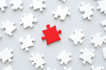 red piece of jigsaw puzzle surrounded by white pieces