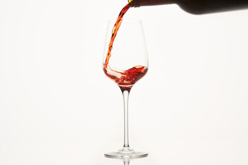 Red wine stream flows, swirls in glassware bowl.