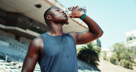 Stadium, black man and fitness with drinking water for wellness, hydration and nutrition on workout...
