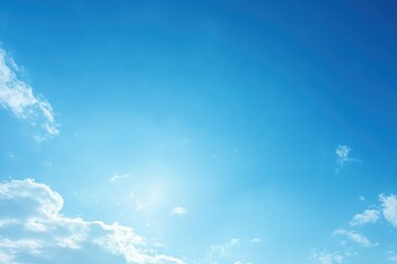 Clear blue sky with bright sunshine and scattered white clouds on a sunny day