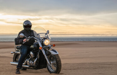 Man on motorcycle in desert during sunset with dramatic clouds &mdash; concept of freedom, travel, solitude, adventure, and outdoor lifestyle in wild open landscapes