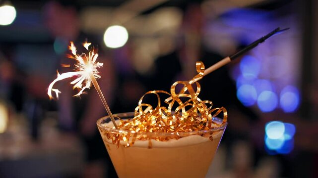 Sparkling cocktail with gold ribbon burning in festive atmosphere