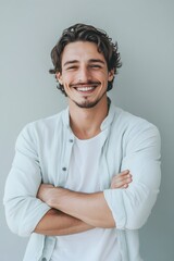 Portrait of smiling young man with folded arms. Smiling joyful cheerful men with crossed hands studio shot, on gray background