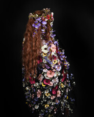 Studio Portraits of Female Model as Celtic Spring Goddess, Floral Fantasy Costume, Inspired by Beltane Pagan Mythology, posing facing away, looking backwards. isolated Dark studio Background