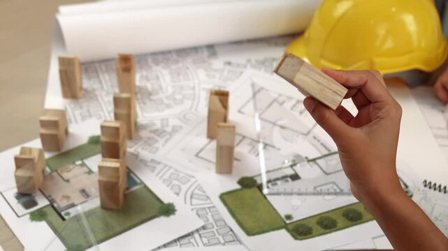 Architect and engineer consider or discuss about building construction using blueprint on table with architectural document, measurement tool and wooden block scatter around at office. Delineation.