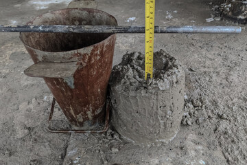 Concrete slump test on construction site showing a slump cone, fresh concrete, and measuring tape...
