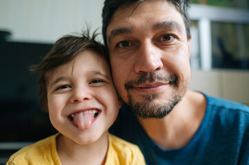 Father and son smiling and fooling around at home