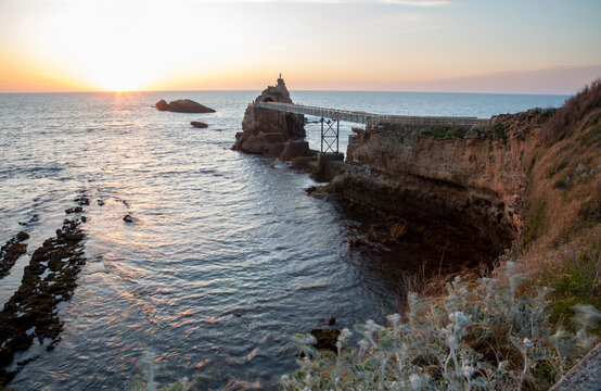 Sunset view of Rocher de la Vierge in Biarritz, France with a scenic coastline and bridge