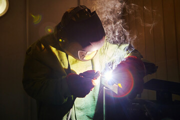 Male in mask welds metal steel, industrial shot