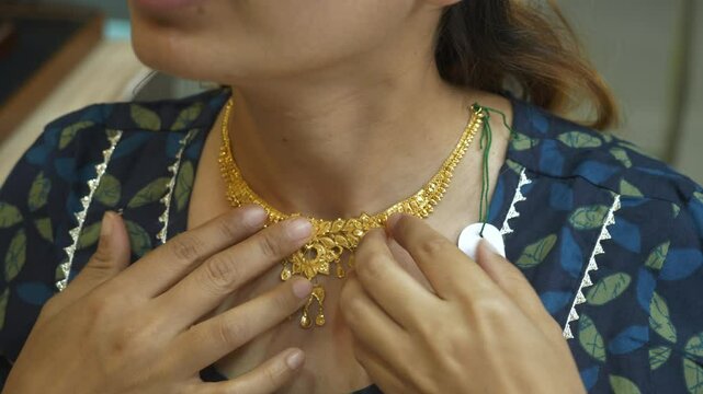 Young Indian asian woman wearing designer gold necklace at gold shop, 18k HUID certified gold necklace, Closeup