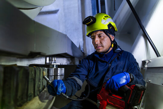 Engineer performing maintenance on a wind turbine nacelle gearbox indoors