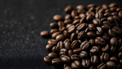 Pile of roasted coffee beans on a dark textured surface background